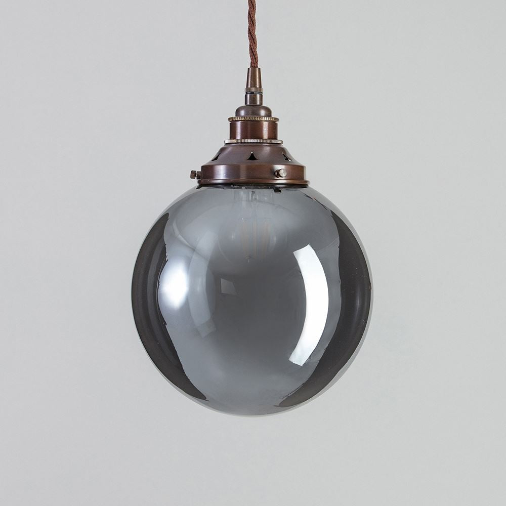 An Old School Electric Globe Blown Smoked Glass Pendant Light hanging from it.