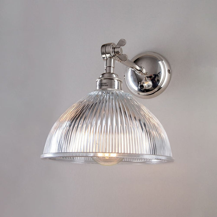 An Old School Electric Prismatic Adjustable Arm Dome Wall Light with a clear glass shade.