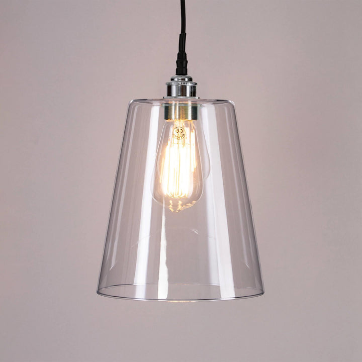 A Tapered Blown Glass Bathroom Pendant Light with a light bulb hanging from it. This Old School Electric lighting fixture elegantly combines an electric light with a sleek and minimalist glass pendant, creating a stunning light fitting for any space.