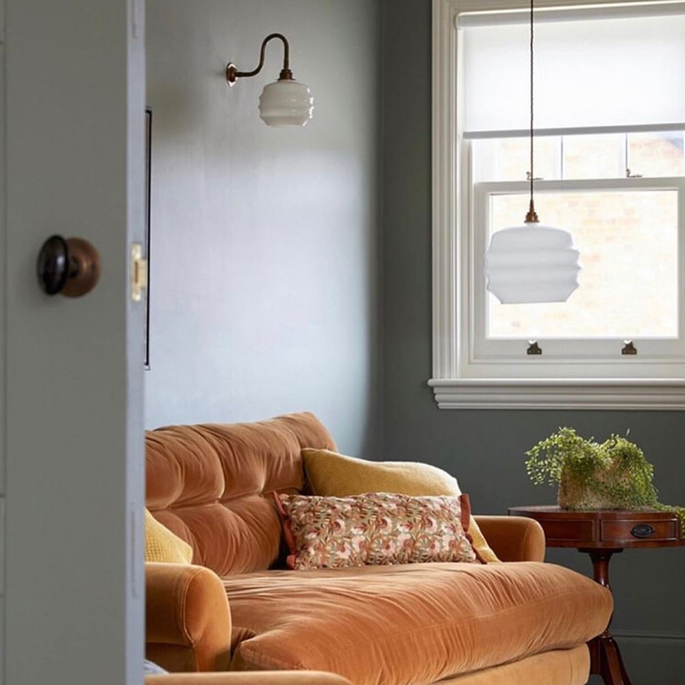 A living room with a yellow Deco Opal Glass Pendant by Old School Electric, timeless elegance, and a window.