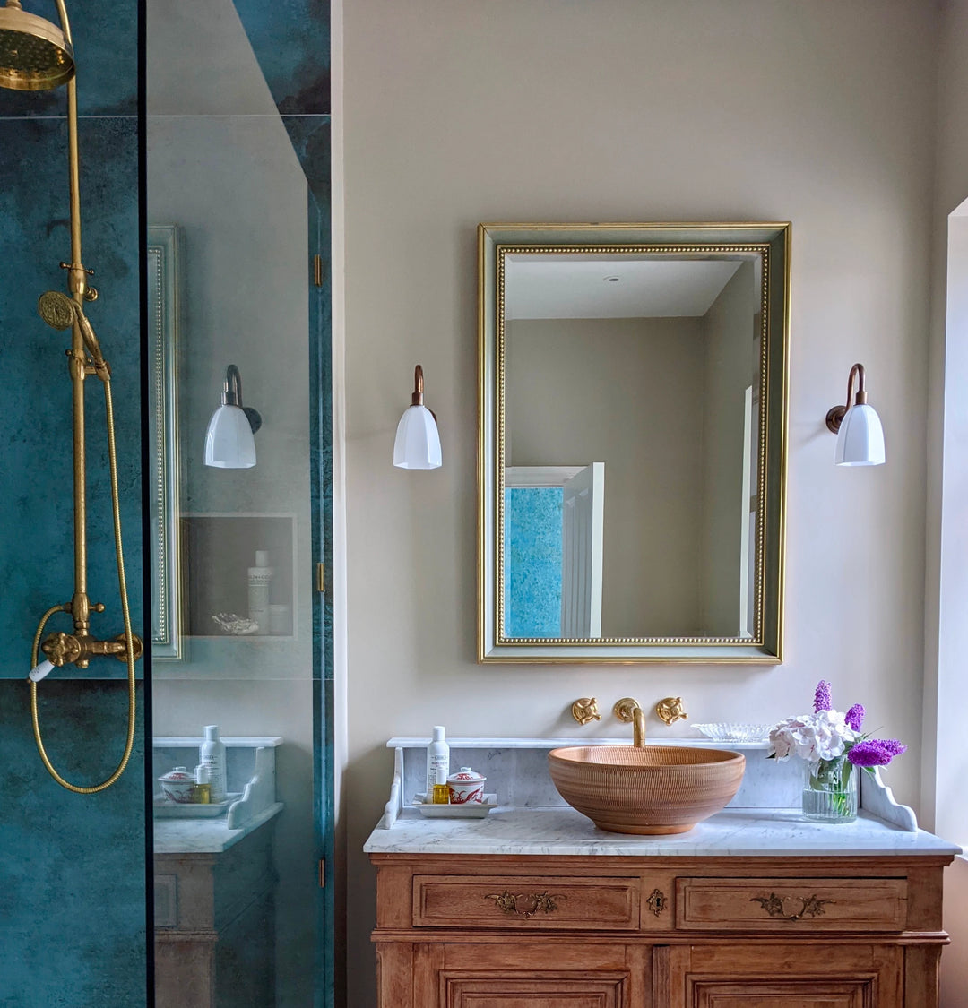 A bathroom with blue walls and a gold sink.