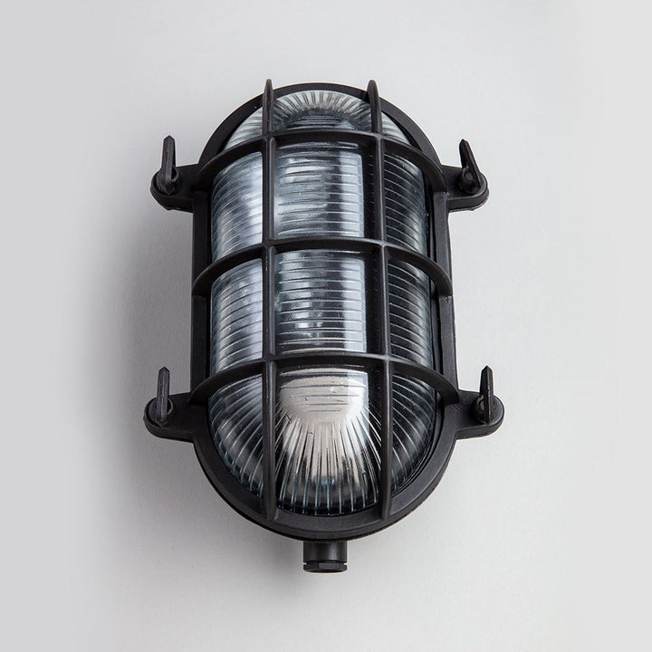 An Oval Bulkhead light fitting with a black cage from Old School Electric.