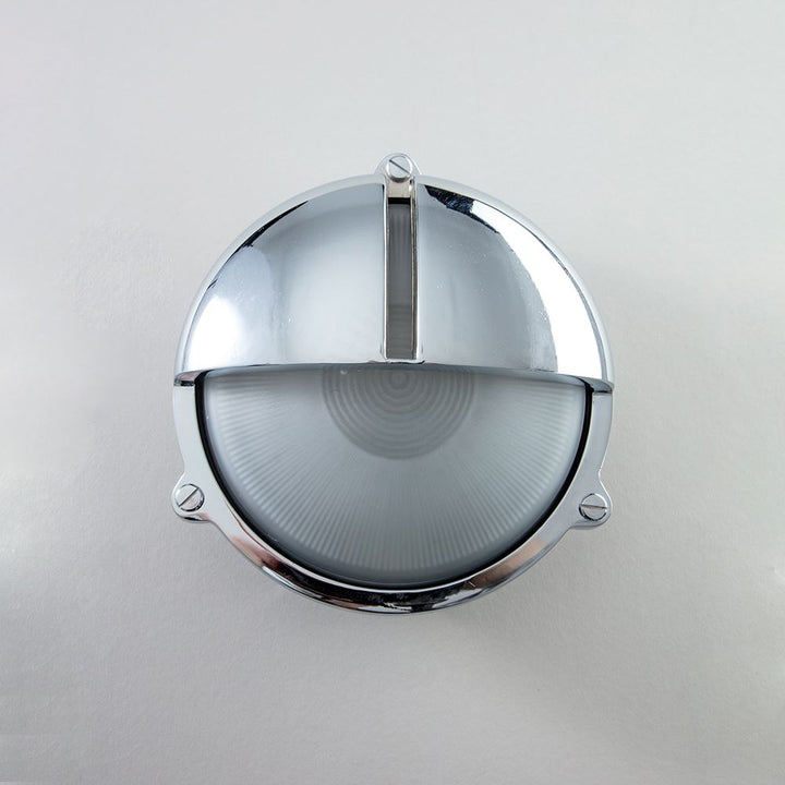 An Old School Electric Round Bulkhead With Eyelid Wall Light on a white wall.