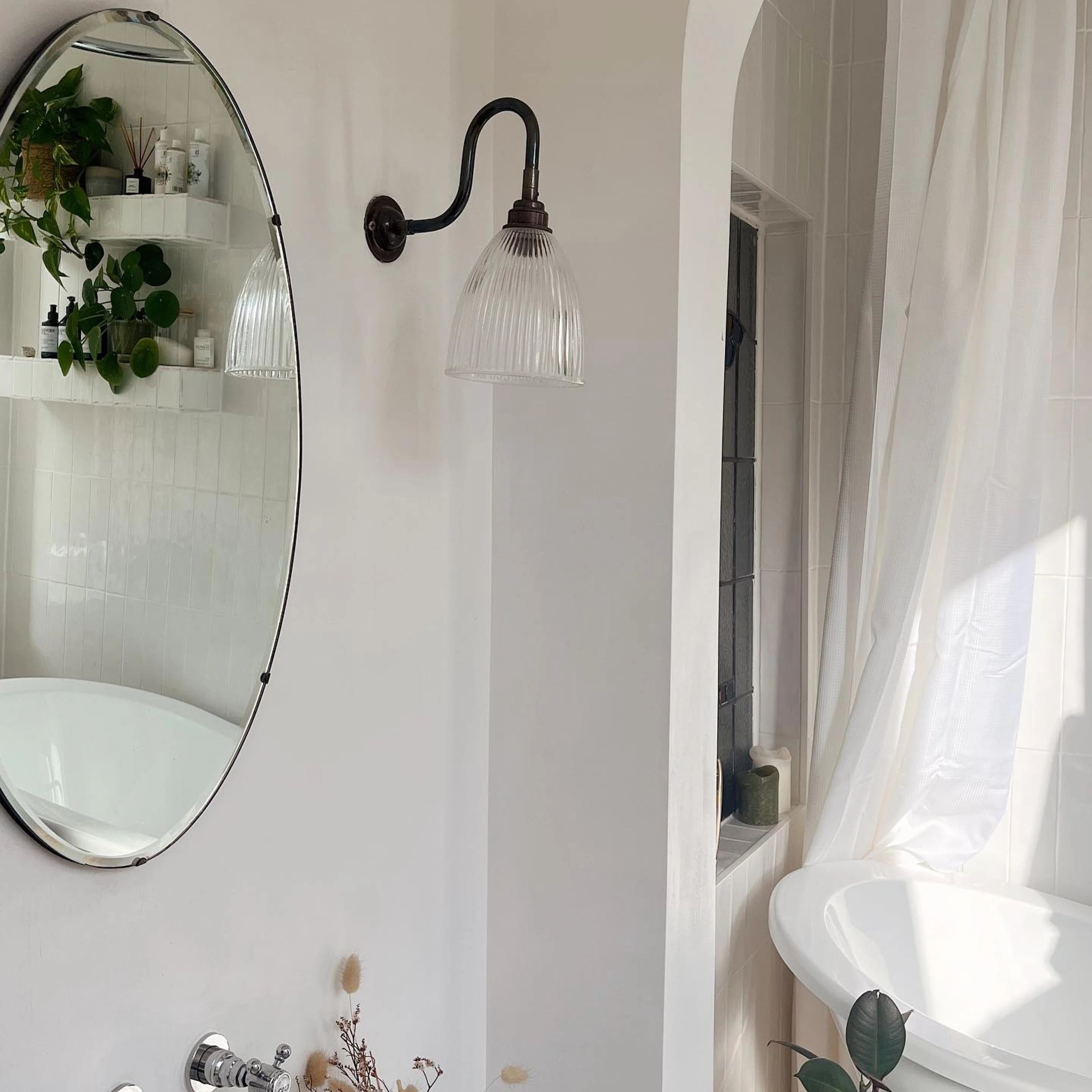 A white bathroom with an oval mirror.