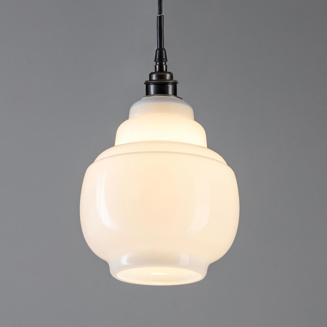An Old School Electric Barrel Opal Glass Bathroom Pendant Light, a lighting fixture, hanging from a gray wall.