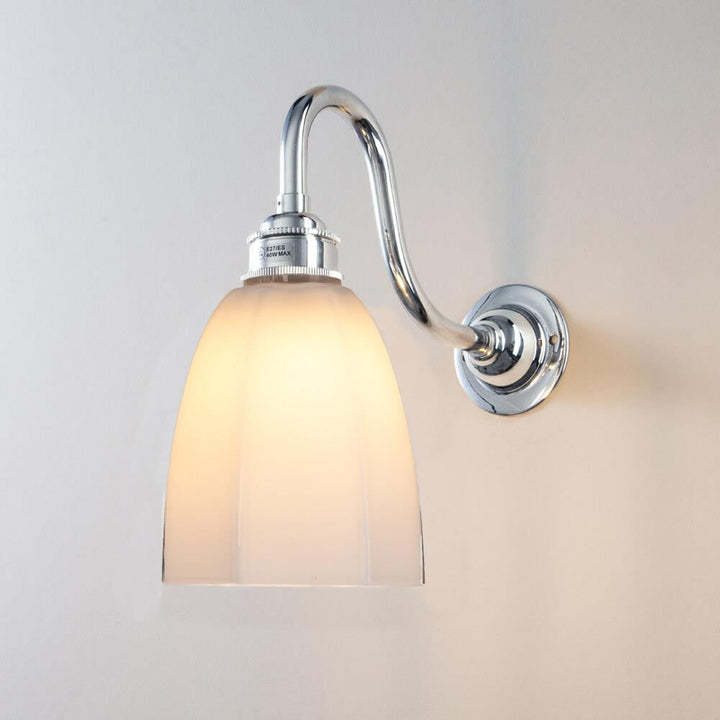 An electric lighting fixture, featuring a Hexagon Bathroom Swan Wall Light from Old School Electric, with a white glass shade.