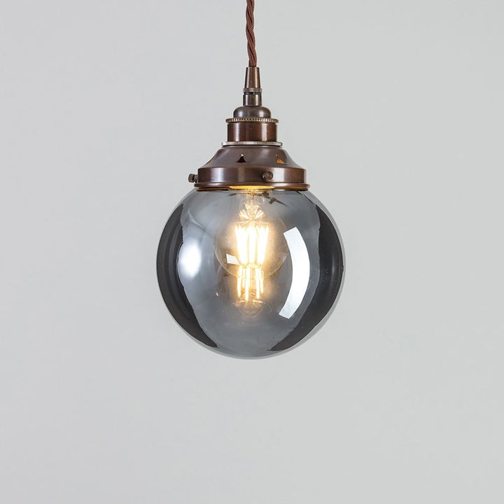 An Old School Electric Globe Blown Smoked Glass Pendant Light with a glass globe hanging from it.