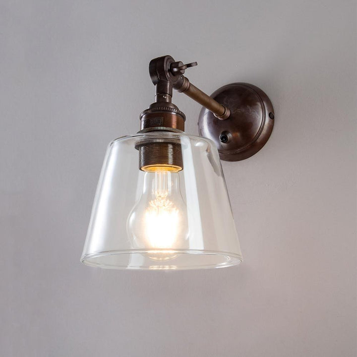 An Old School Electric Glass Adjustable Arm Wall Light with a glass shade. This electric light fitting enhances any space with its stylish and modern design features.