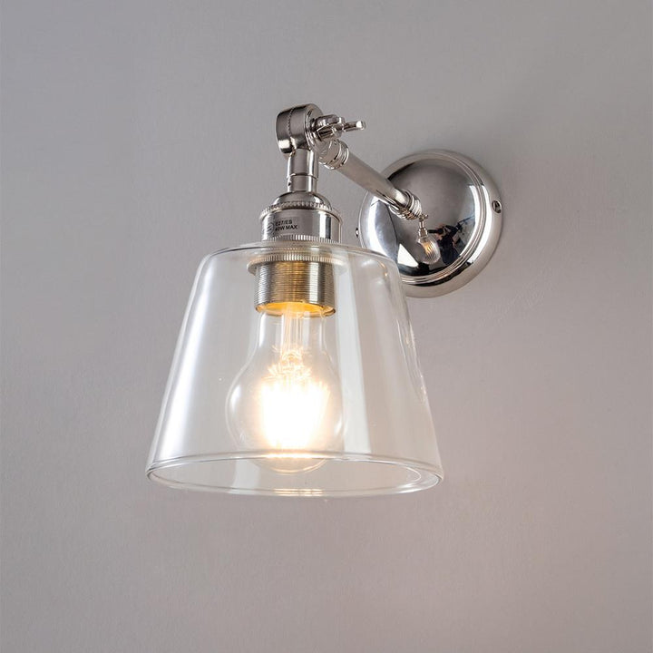 An Old School Electric Glass Adjustable Arm Wall Light illuminating a white wall.