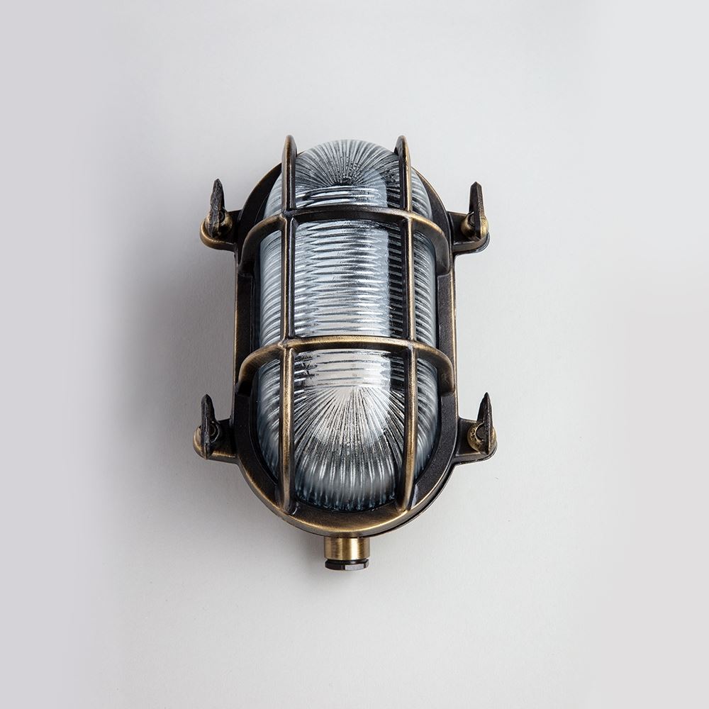 An Oval Bulkhead light fixture with a cage and electric lights on a white background by Old School Electric.