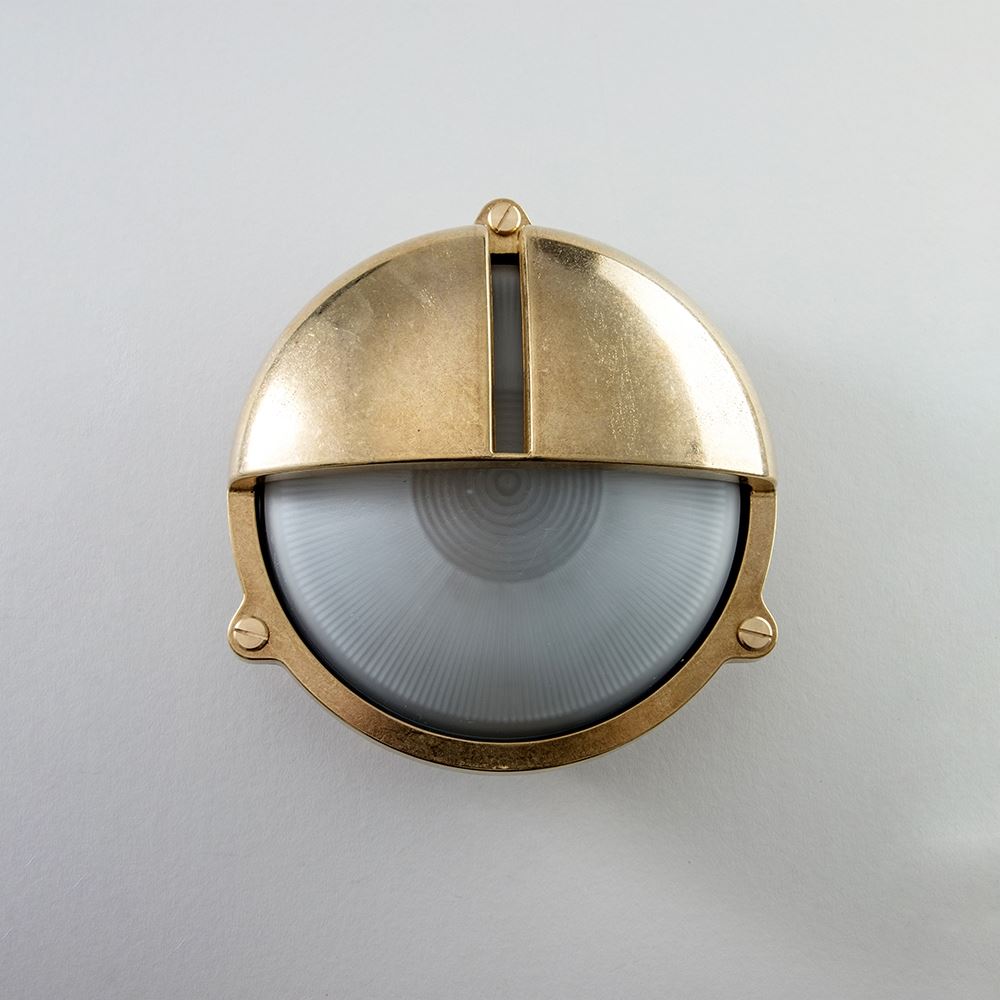 An Old School Electric Round Bulkhead With Eyelid Wall Light fixture illuminating a white wall.