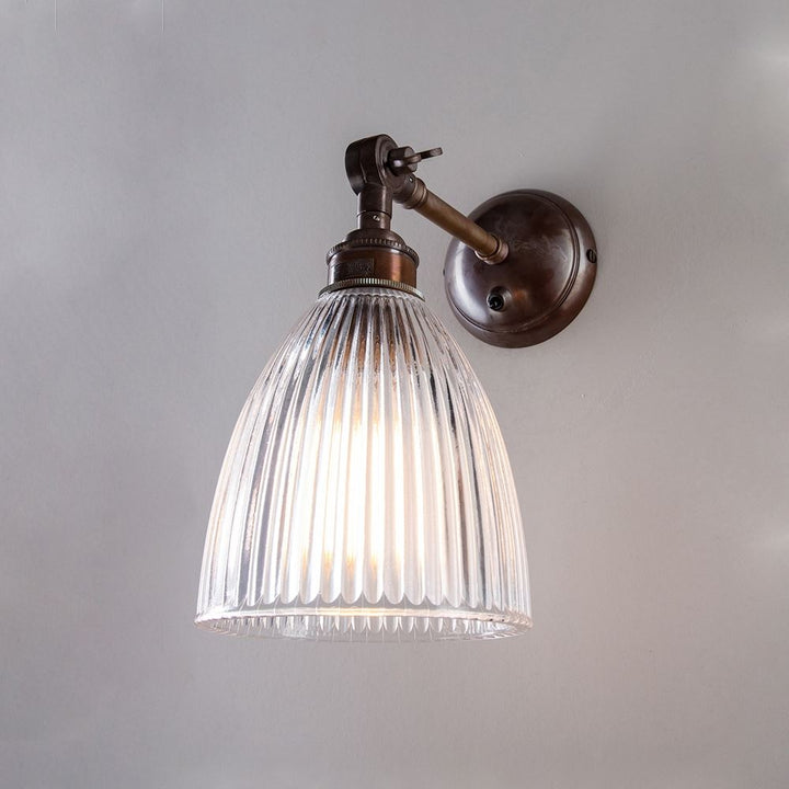 An Old School Electric Elongated Prismatic Adjustable Arm Wall Light with a glass shade on a wall.