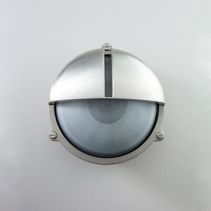 An Old School Electric Round Bulkhead With Eyelid Wall Light mounted on a white wall.