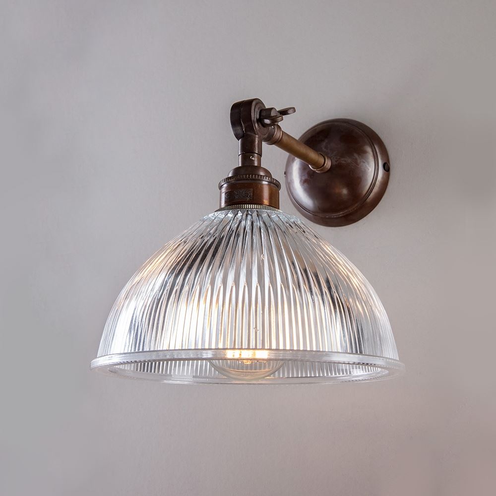 An Old School Electric Prismatic Adjustable Arm Dome Wall Light with a glass shade on a wall.