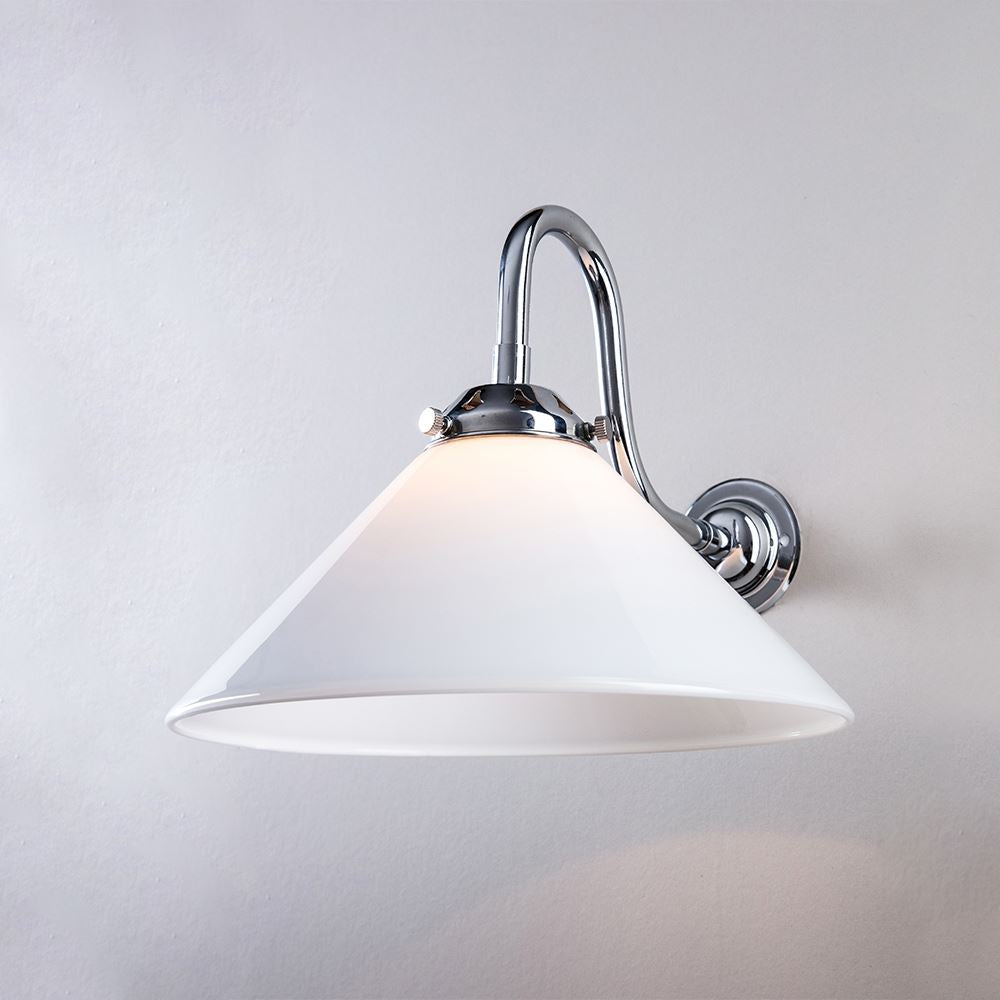 Description: A Conical Glass Wall Light (B22) by Old School Electric illuminating a white wall.