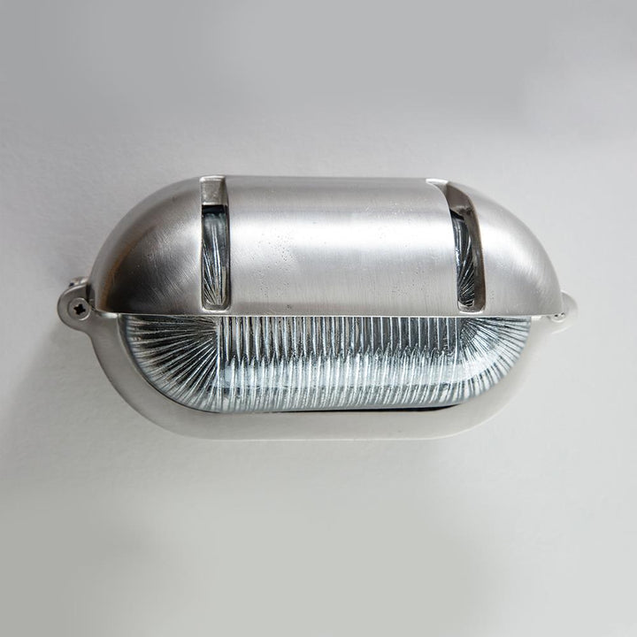 An Old School Electric Oval Bulkhead With Eyelid Wall Light on a white wall.