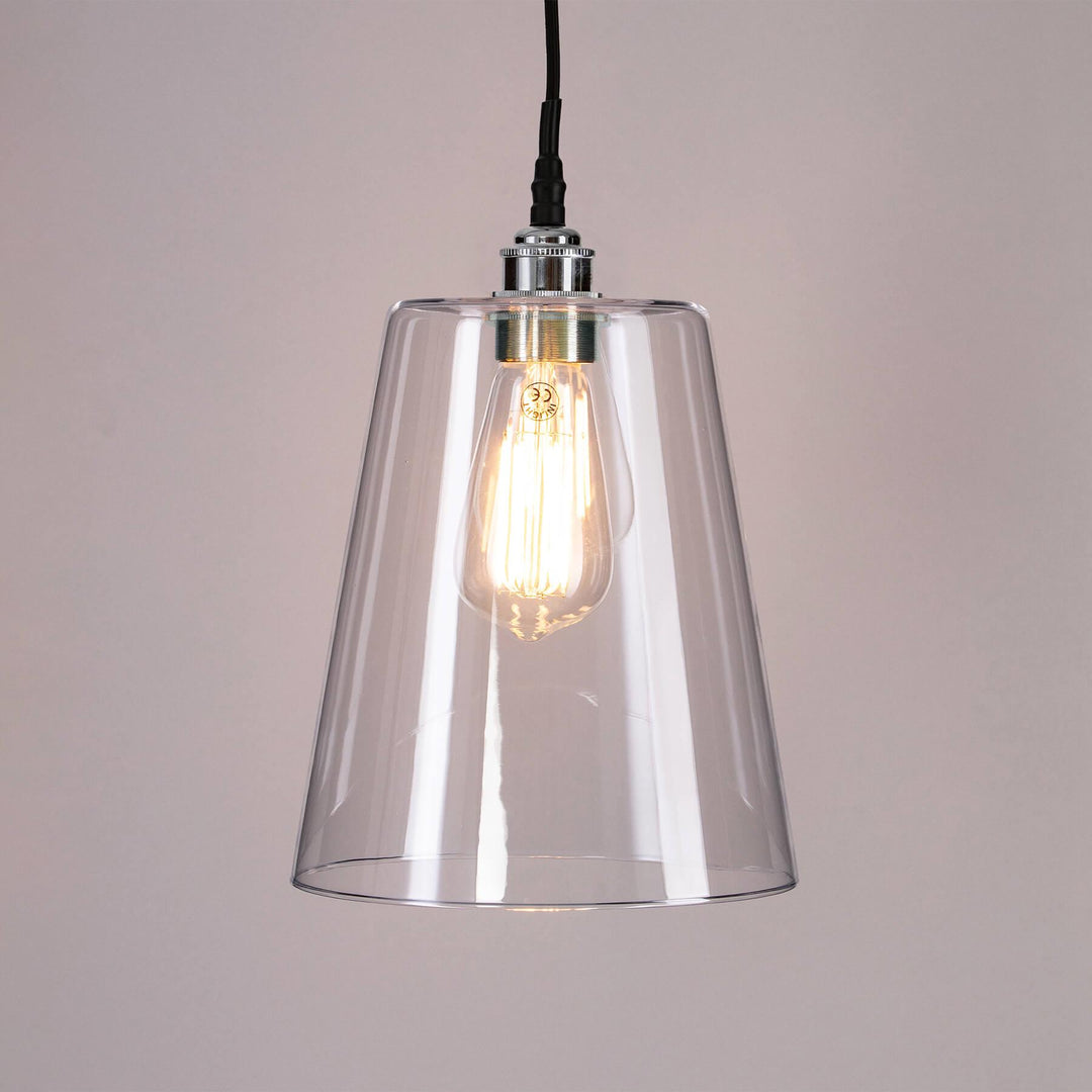 A Tapered Blown Glass Bathroom Pendant Light with a light bulb hanging from it. This Old School Electric lighting fixture elegantly combines an electric light with a sleek and minimalist glass pendant, creating a stunning light fitting for any space.