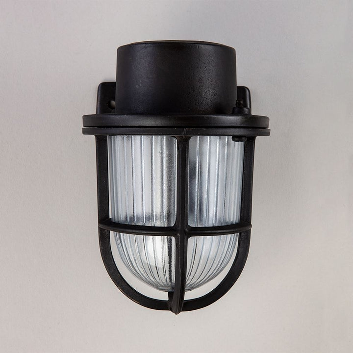 A black Faros Mini Yacht wall light with a clear glass shade by Old School Electric.