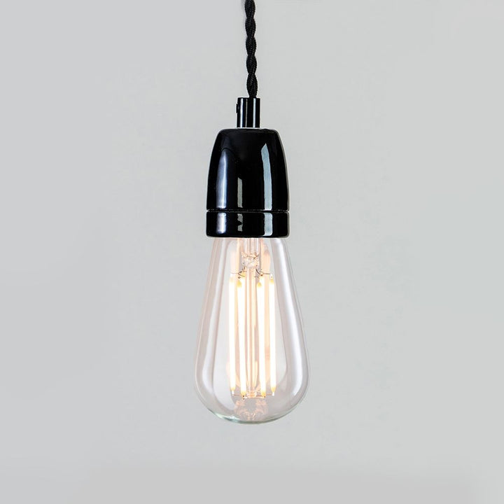 A black Ceramic Cable Set lighting fixture with an electric light hanging from a black cord by Old School Electric.