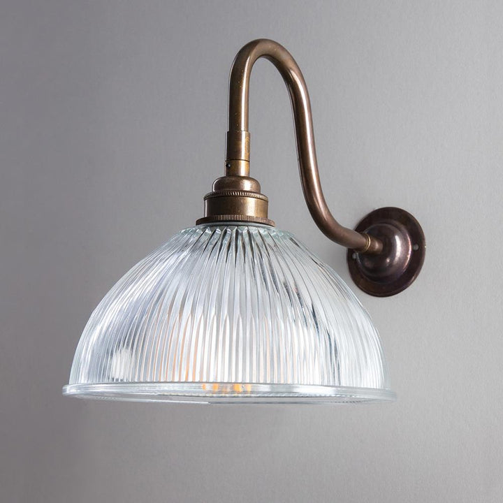 An Old School Electric Prismatic Dome Bathroom Swan Arm Wall Light fixture with a glass shade.
