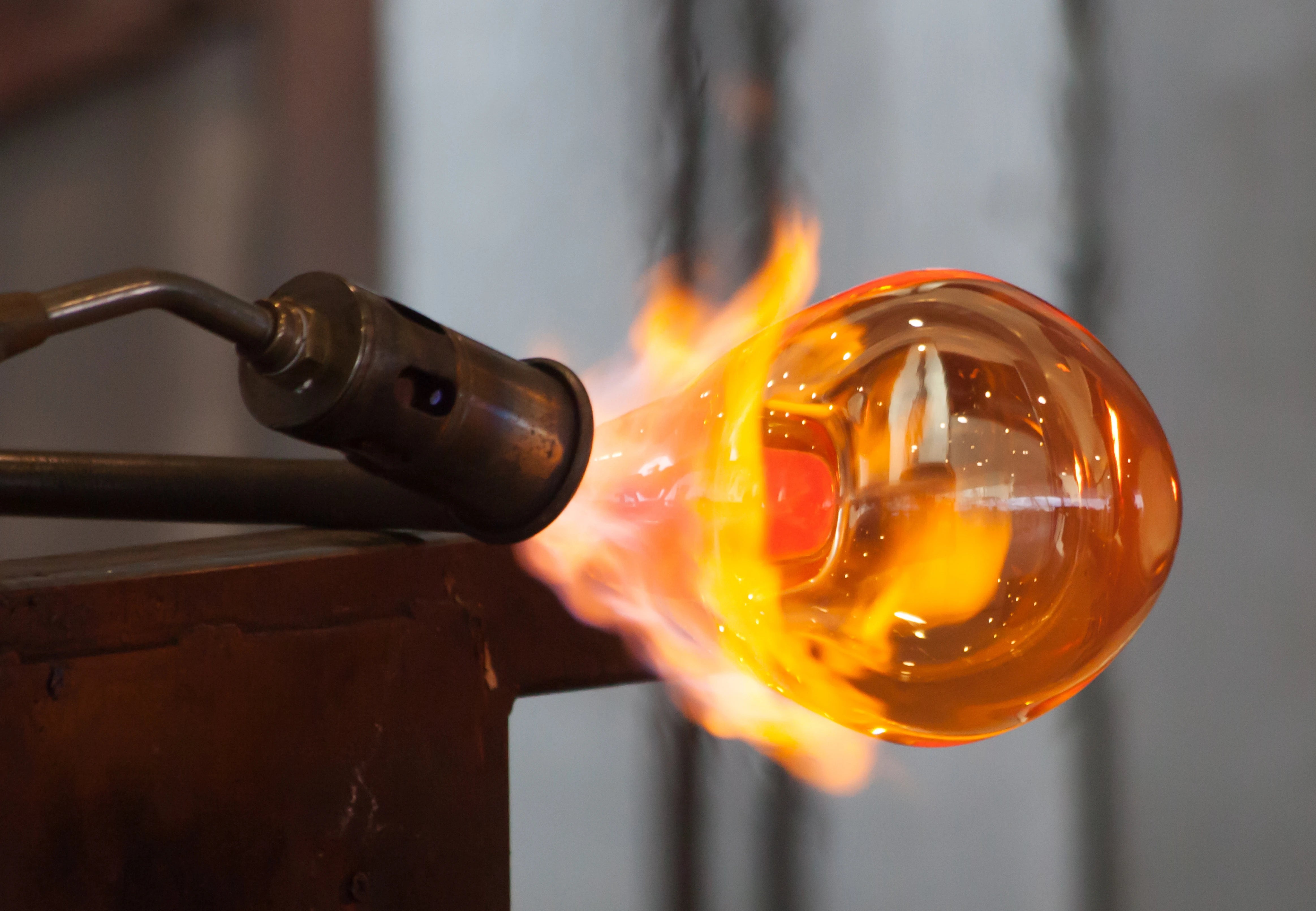 A glass blower is making a glass ball.