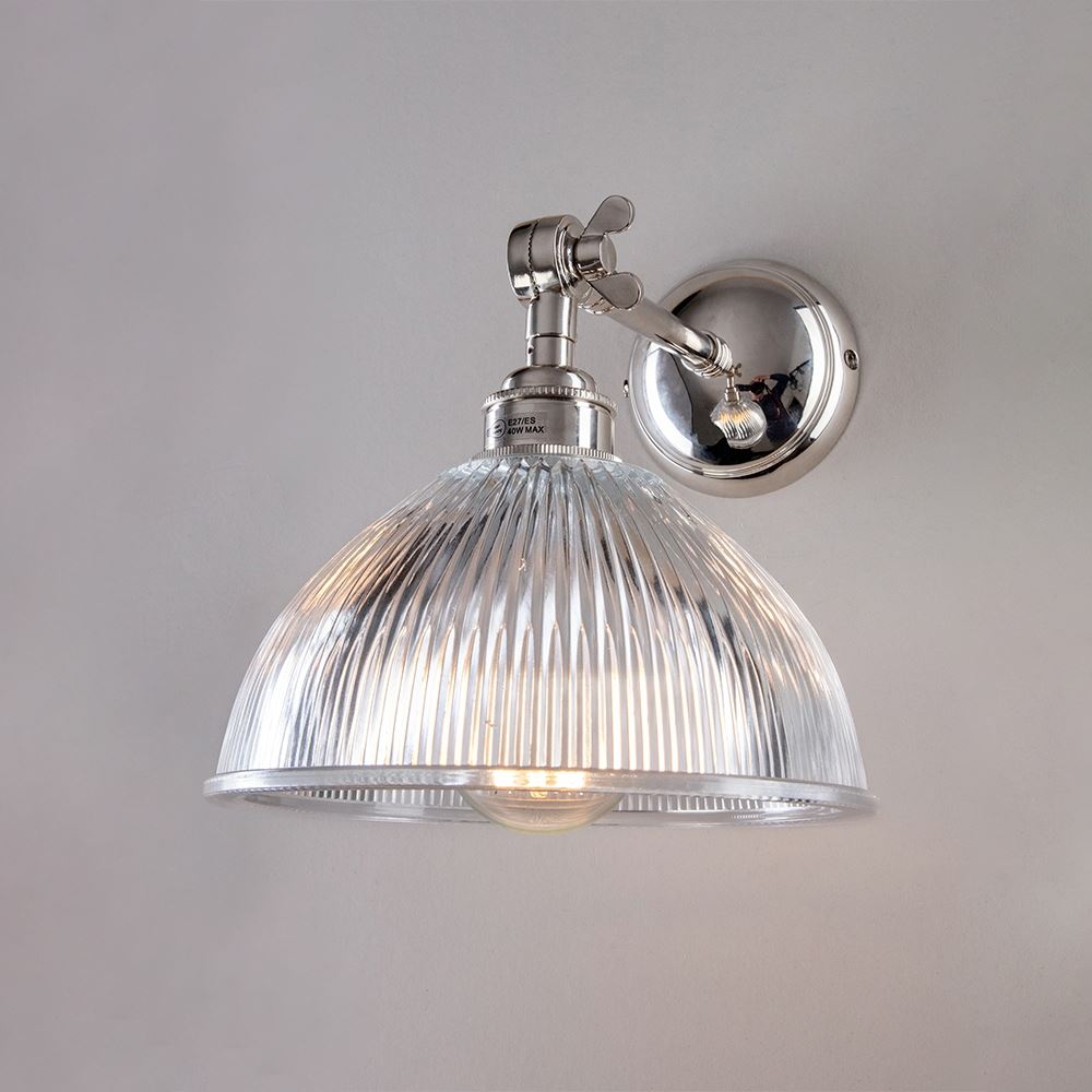 An Old School Electric Prismatic Adjustable Arm Dome Wall Light with a clear glass shade. It is a stylish lighting fixture that emits soft electric lights, creating an inviting ambiance in any space.