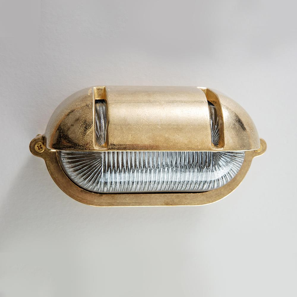 An Oval Bulkhead With Eyelid Wall Light fixture on a white wall. (Brand: Old School Electric)