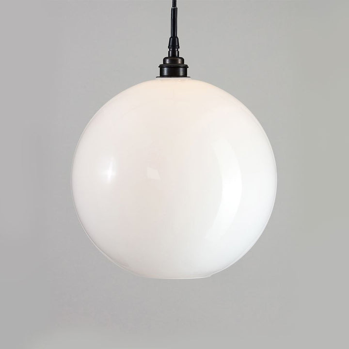 An Adderley Pendant Light by Old School Electric, with a white sphere, hanging from a black chain.