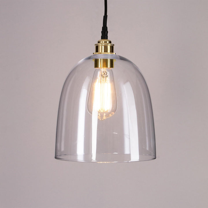 An Old School Electric Bell Blown Glass Bathroom Pendant Light with a clear glass shade and brass base, perfect for adding elegance to any bathroom.