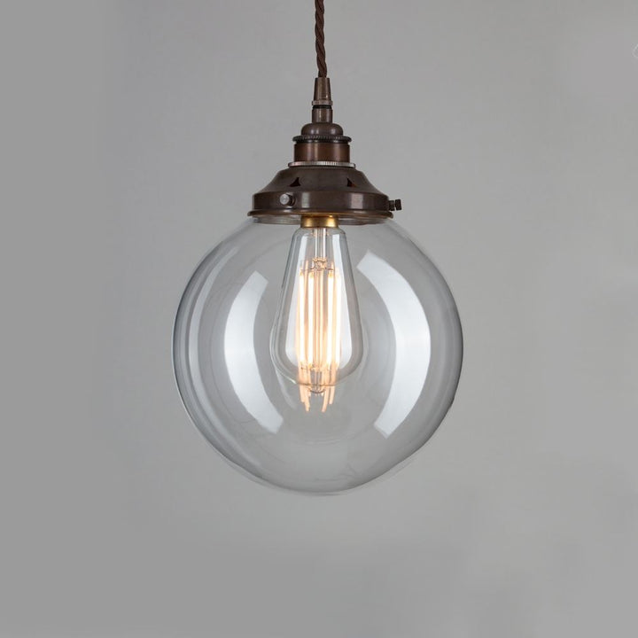 An Old School Electric Globe Blown Glass Pendant Light with a brass chain. This lighting fixture is perfect for adding a touch of elegance to any room. The glass globe provides a soft and warm glow, while the brass chain adds a stylish accent.